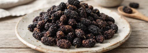 Sun-dried black mulberries piled on a ceramic plate